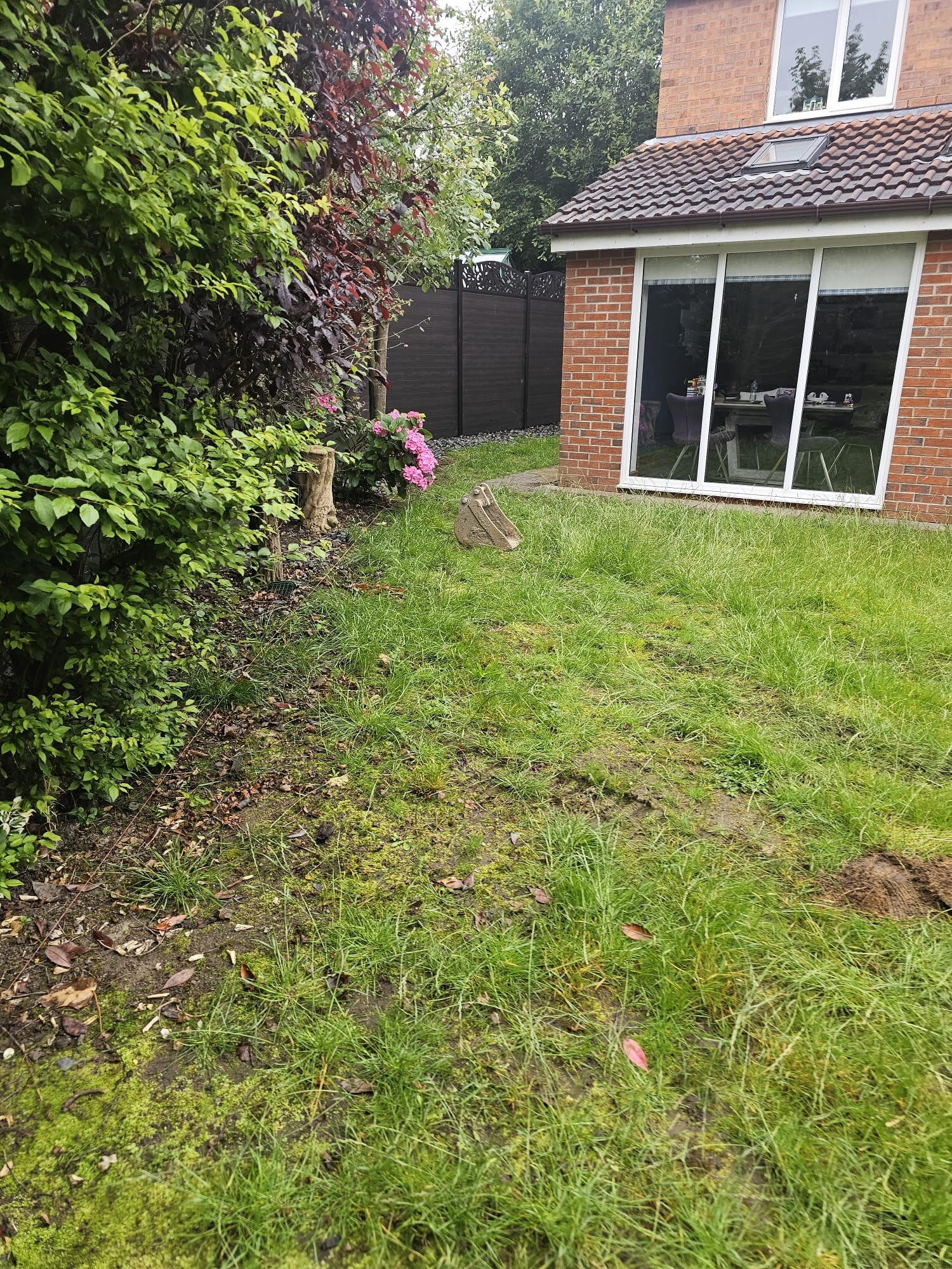 Mossy uneven lawn beside the existing conservatory before strip-out