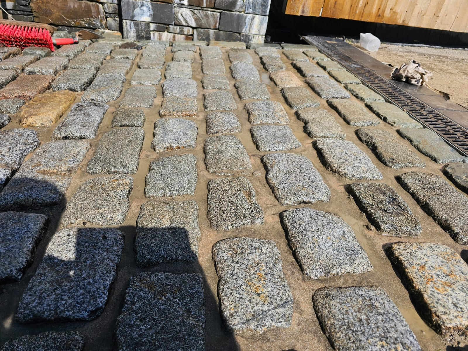 Reclaimed granite setts being bedded and brushed with kiln-dried sand