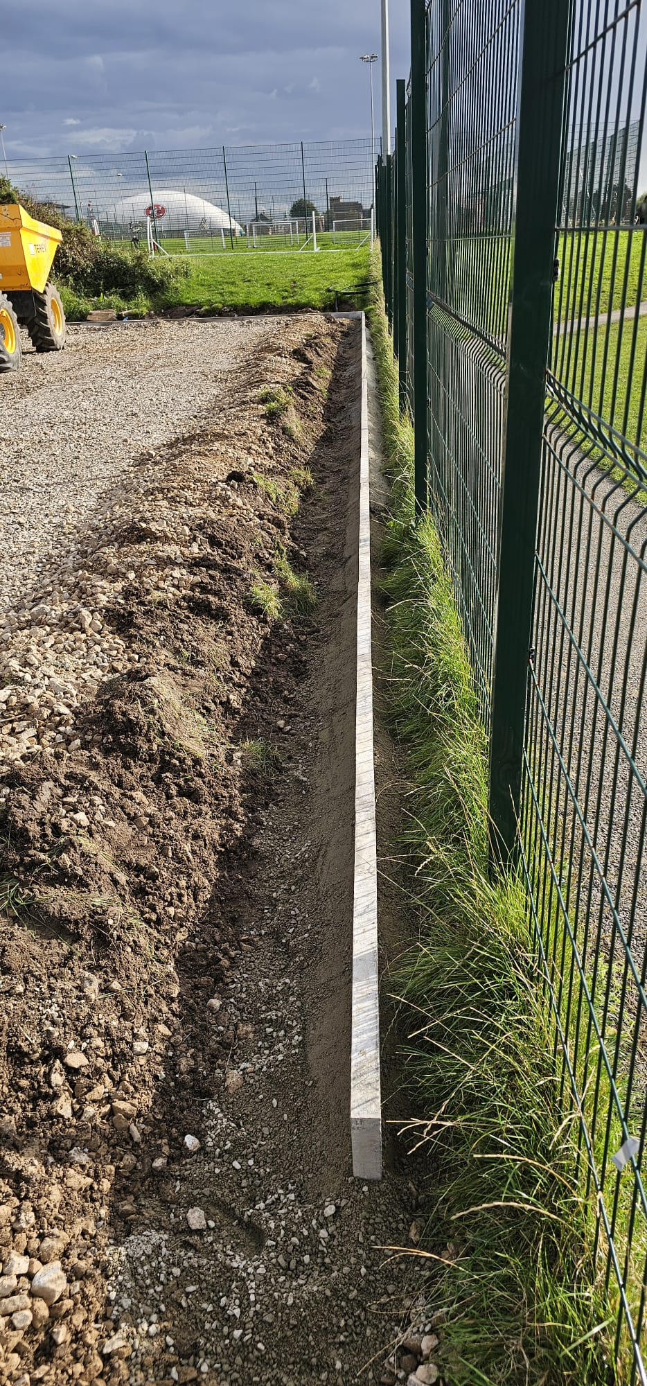 Concrete edge kerb against existing pitch fenceline