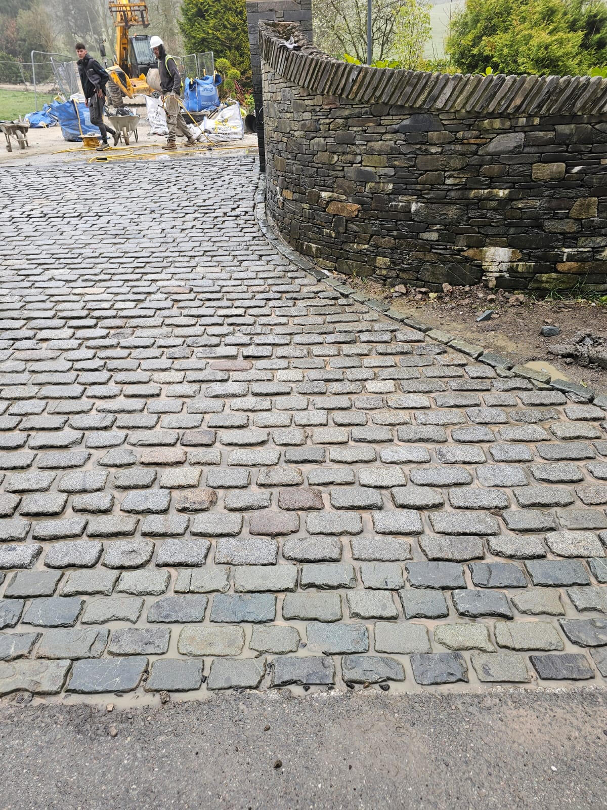 Cobbled driveway approach with curved dry-stone wall and team on site