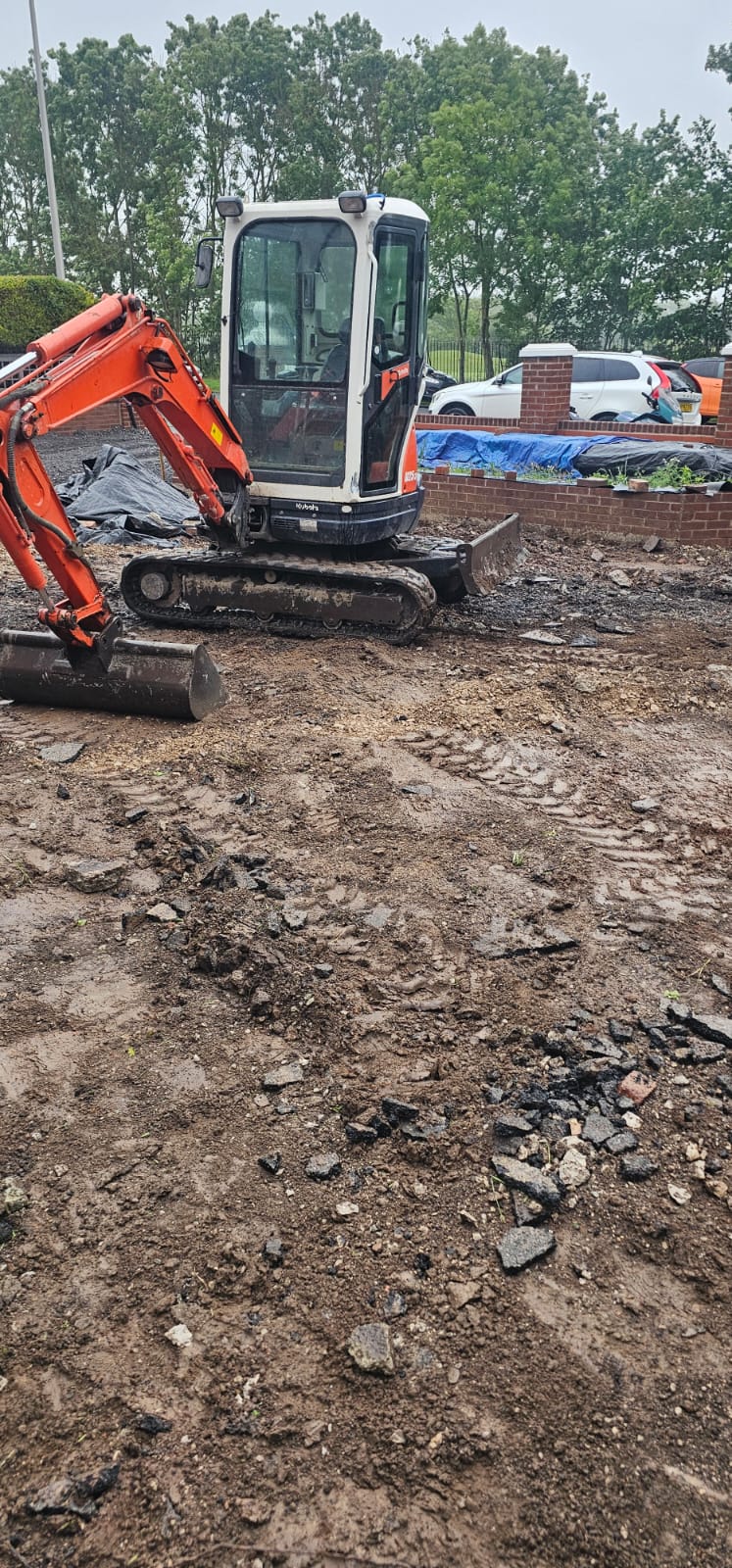 Kubota mini-digger working over a freshly graded driveway subbase