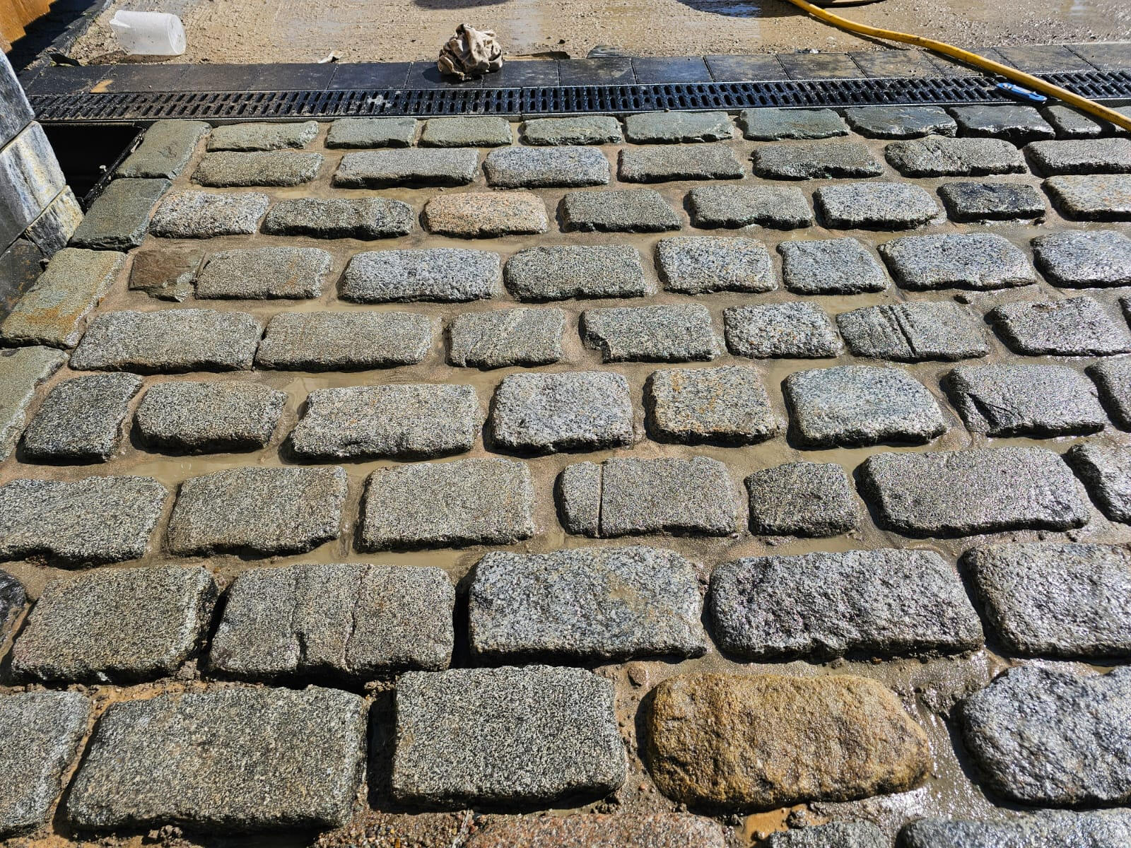 Close-up of cobbled granite paving with linear ACO drainage channel