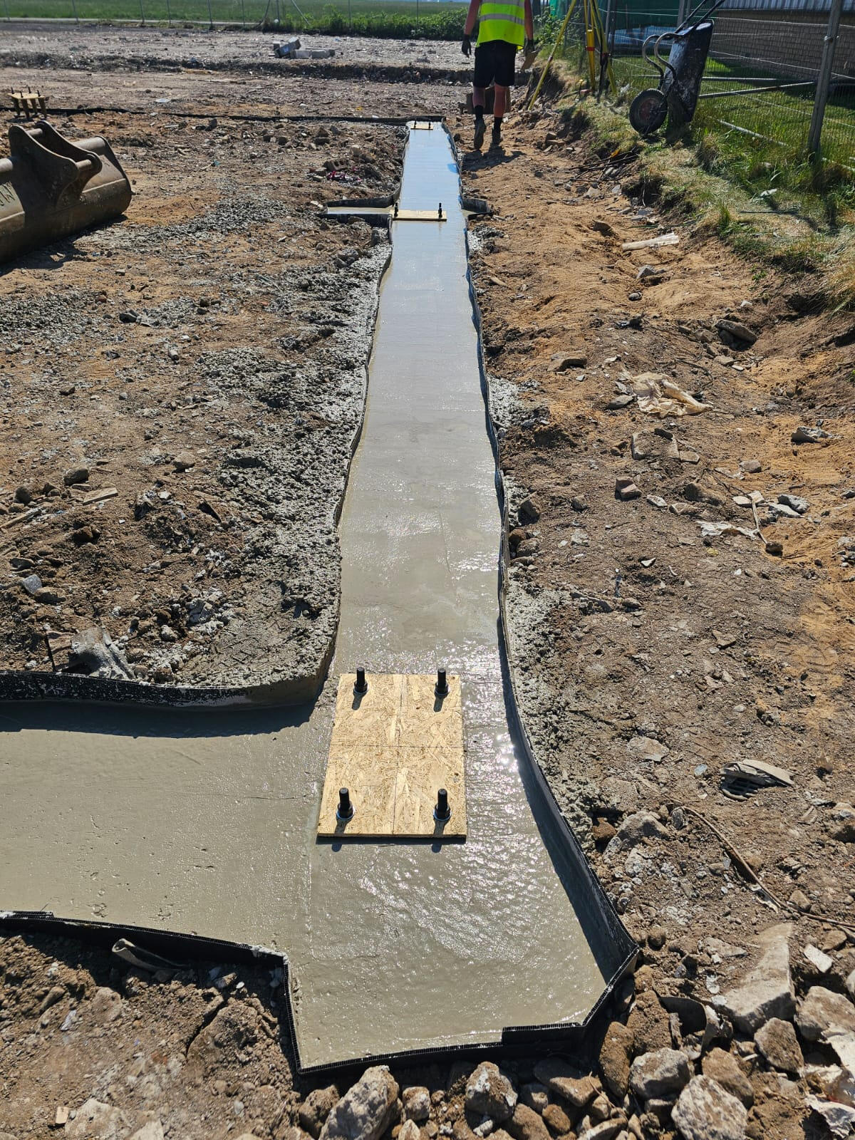 Poured concrete strip footing with cast-in holding-down bolt baseplate