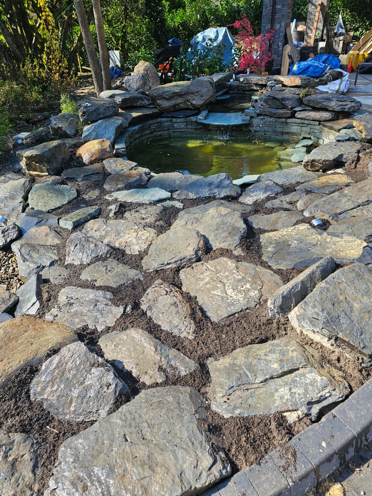 Reclaimed stone patio and ornamental pond with cascading water feature