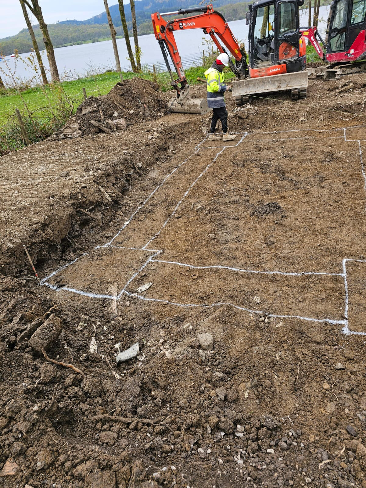 Foundation footprint marked out in spray paint with mini-excavators on standby