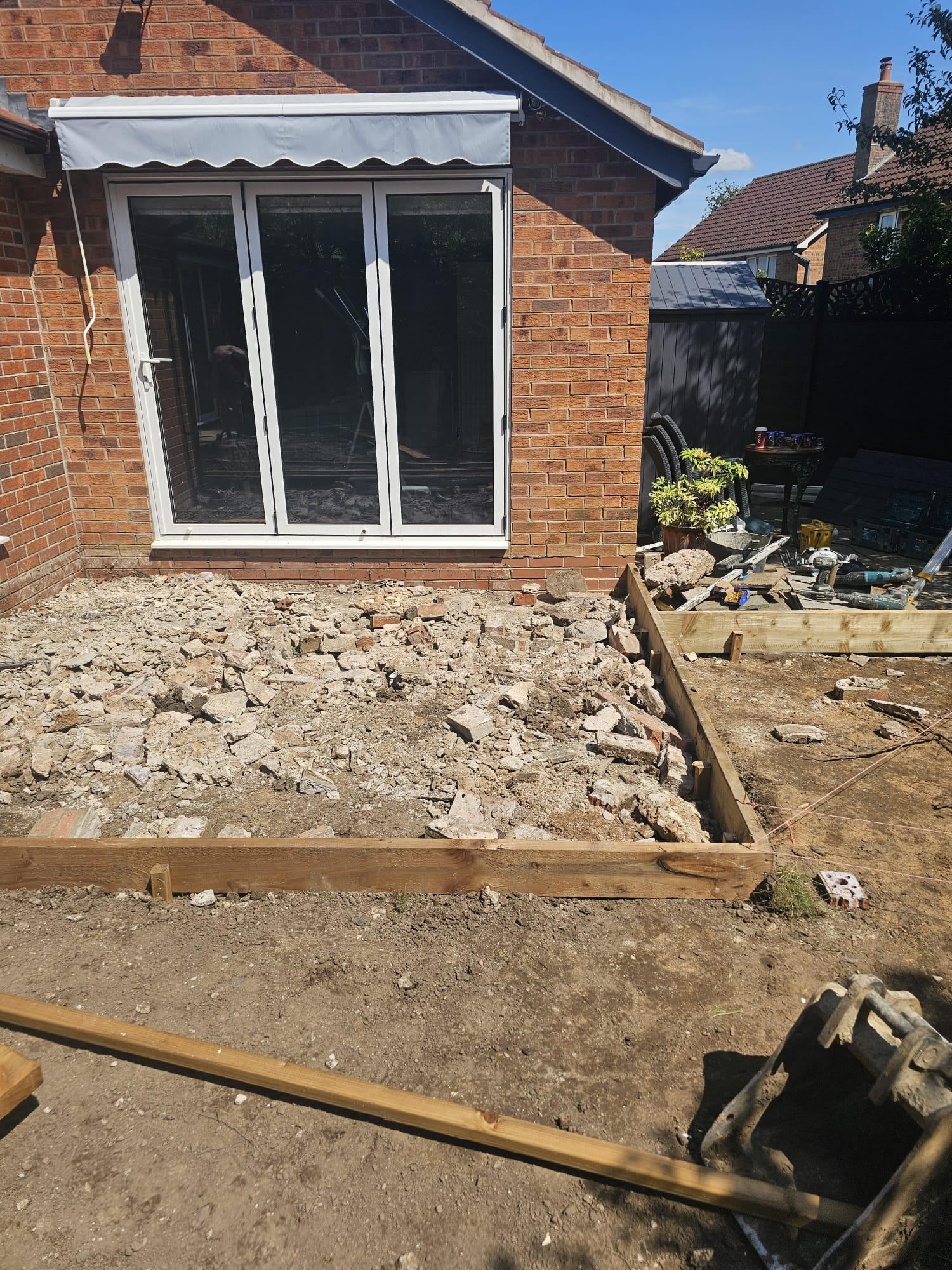Compacted MOT sub-base in front of the bi-fold doors ready for sandstone patio
