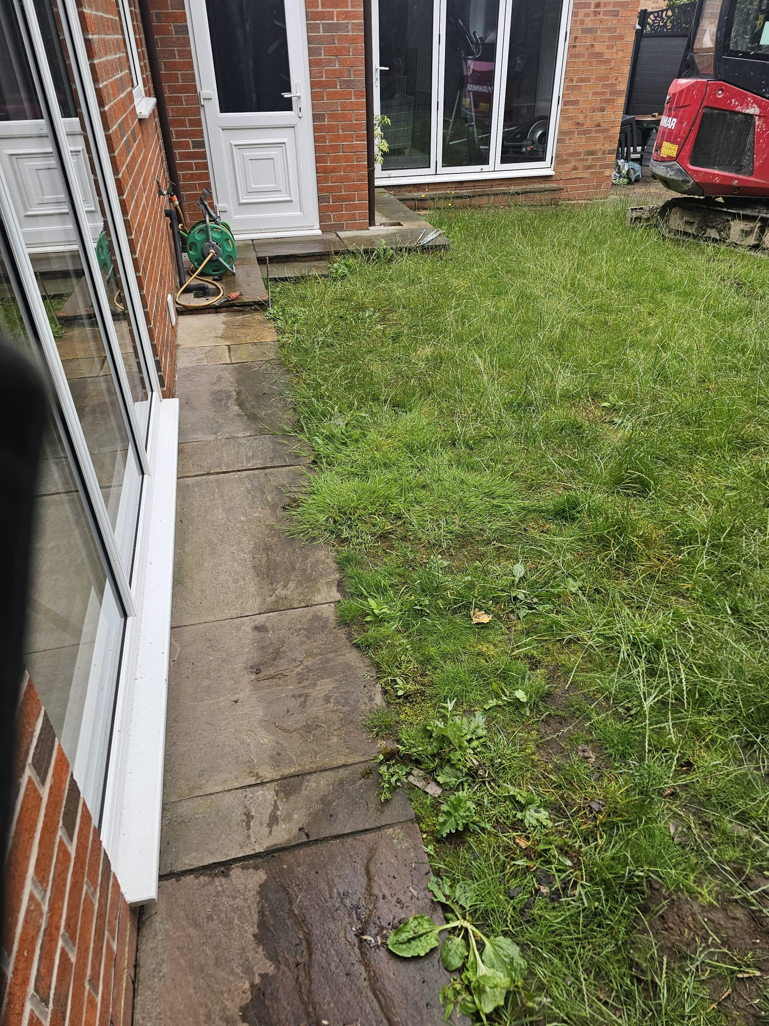 Worn patio slabs and patchy grass running up to the rear of the bungalow