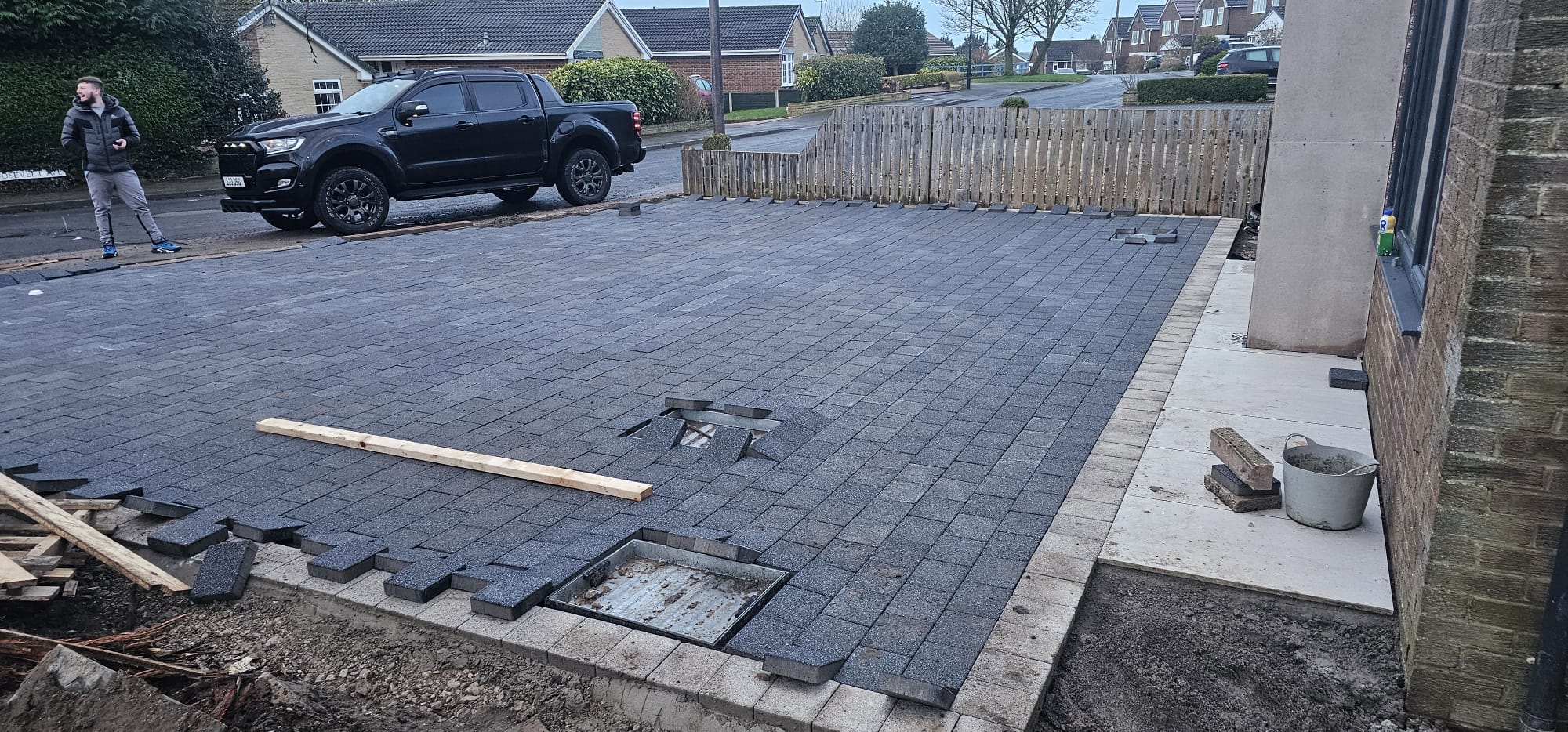 Large charcoal block-paved driveway with cast-in inspection covers, freshly laid